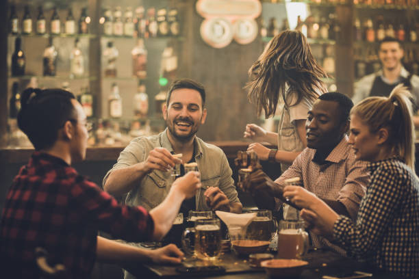 Group of happy friends having fun while toasting with vodka shots in a pub.