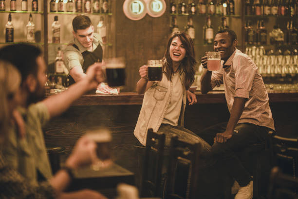 istock Happy couple at bar counter having fun while toasting with the couple at the table. 938400934