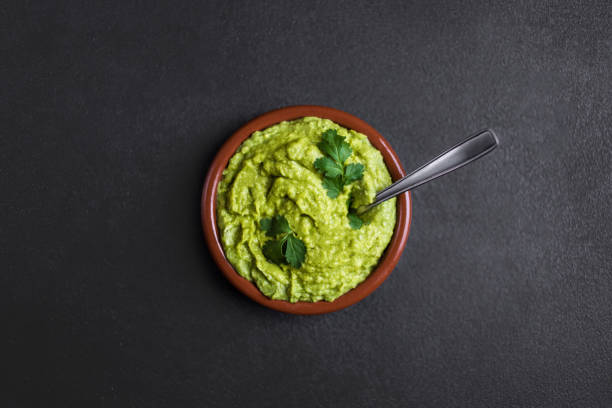 istock Guacamole spread  in clay bowl on a black background. Avocado sauce. Top view with copy space 938401302