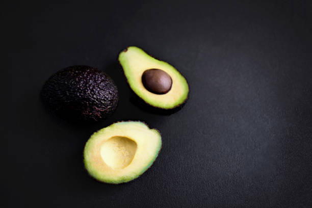 istock Avocado on a black background. Half of avocado close up. Top view. Copy space 938401318