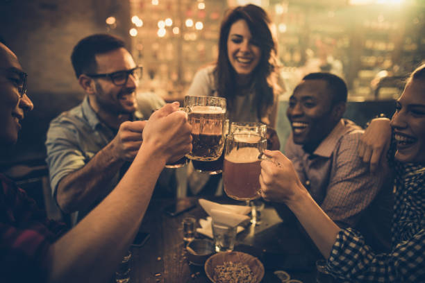 istock Group of young joyful friends having fun while toasting with beer in a pub. 938401346