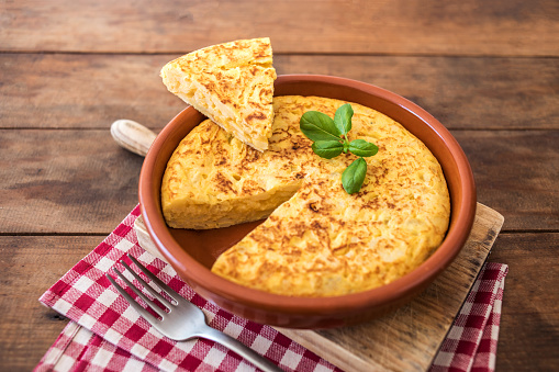 Spanish potato omelet called tortilla de patatas on a rustic wooden texture with a place for text\