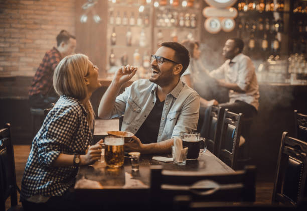 playful couple having fun with peanut during their night out in a pub. - beer nuts imagens e fotografias de stock