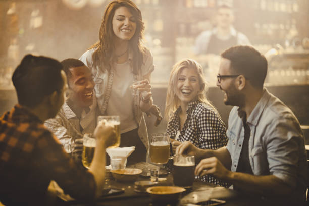 istock Group of cheerful friends having fun while talking during the night out in a pub. 938402692
