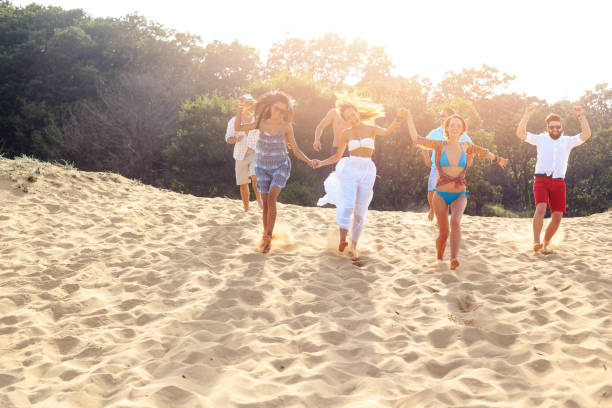 istock Group of young people running on sand 938404566