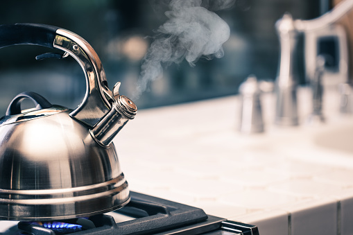 Tea Kettle with Steam on top of a stove