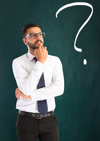 young businessman looking up and question arises his mind on green backgound