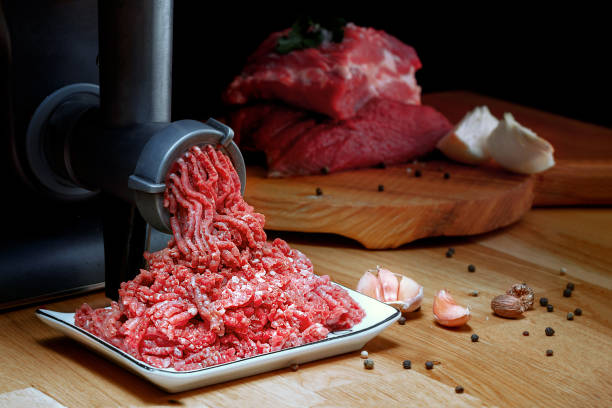 Minced meat coming out from grinder. Healthy homemade minced meat. Dark background. Horizontal view photo. Place for copyspace. stock photo