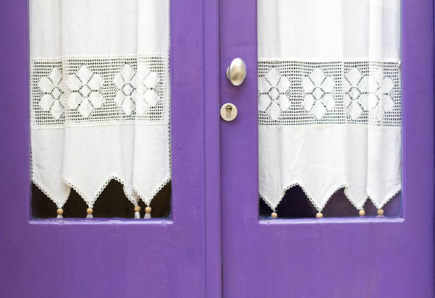Sicily: Pretty Lace Curtains Hang in Purple Windows. Shot in Scicli, Ragusa Province. Copy space at the bottom of the frame.