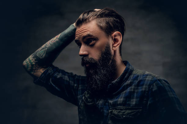 istock Bearded male with tattoo on arm touches his head. 938418940