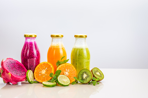 Three flavours of fruit juice in bottles with a straw islolated on white background with copy space.