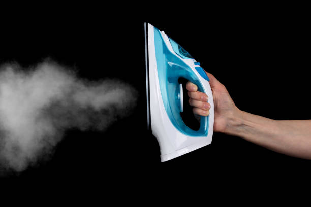 istock Modern electric iron with steam isolated on black 938422632