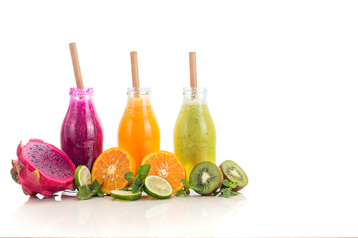 Three flavours of fruit juice in bottles with a straw islolated on white background with copy space.