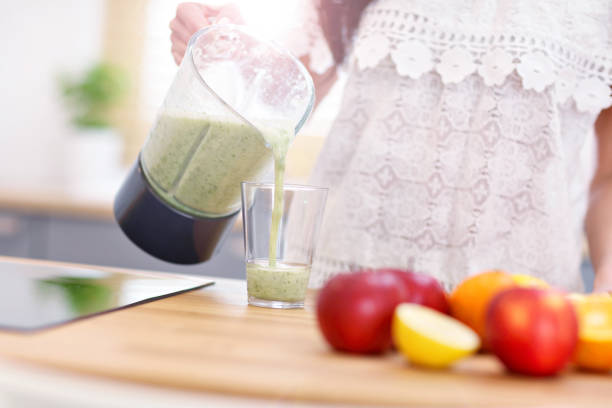 istock Fit smiling young woman preparing healthy smoothie in modern kitchen 938430020