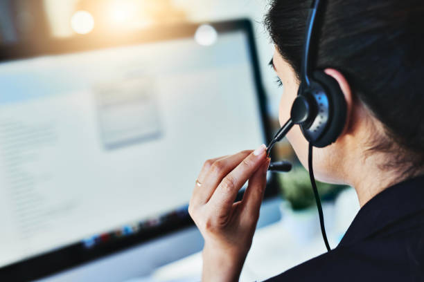 Managing the day's inquiries Rearview shot of a young woman working in a call centre customer relationship management stock pictures, royalty-free photos & images