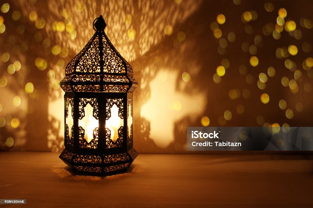 Ornement lanterne arabe avec combustion bougie allumé pendant la nuit et scintillants de lumières dorées bokeh. Carte de voeux Fête, invitation pour le mois sacré musulman Ramadan Kareem. Fond sombre - Photo de Ramadan libre de droits