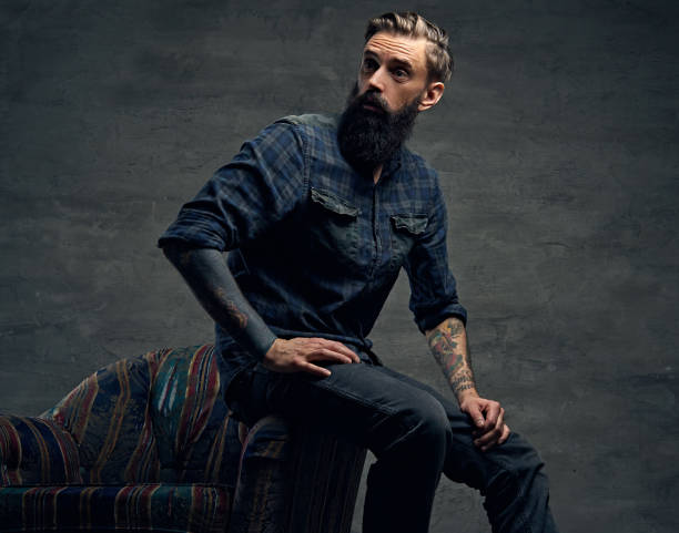 istock Tattooed bearded male sits on a chair. 938431216