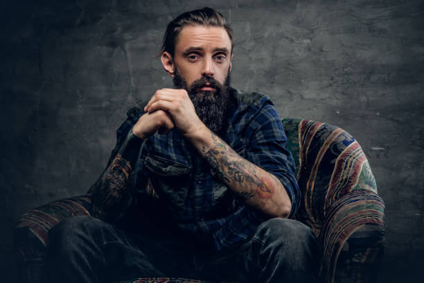 istock Tattooed bearded male sits on a chair. 938431666