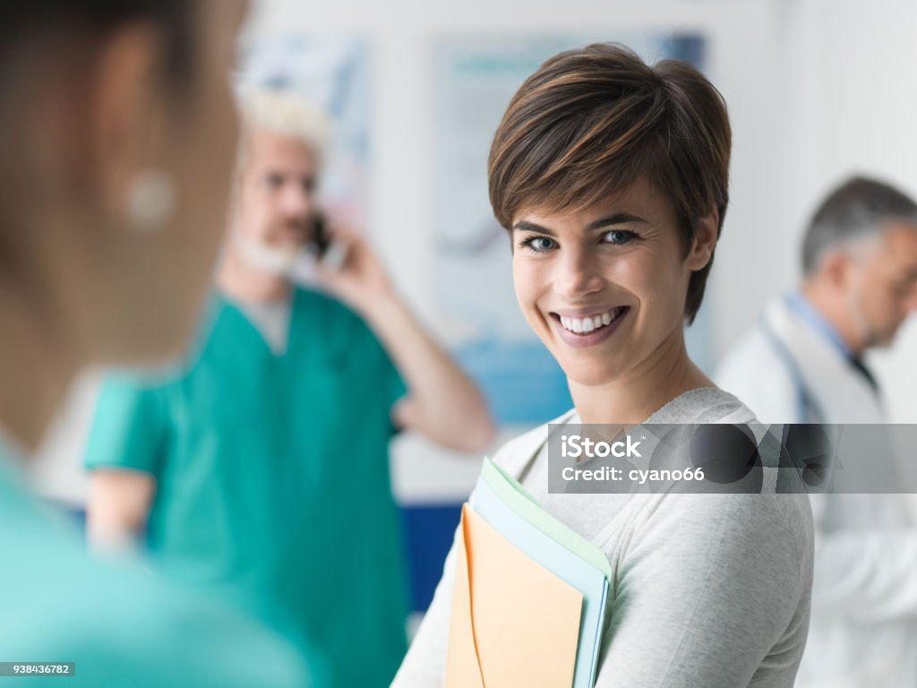 Patient at the hospital Confident woman at the hospital holding medical records and smiling at camera Healthcare And Medicine Stock Photo