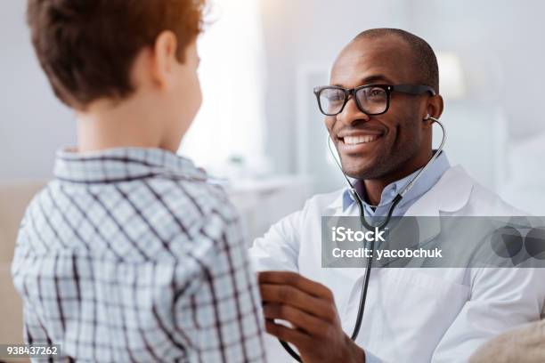 Afro American Male Doctor Examining Boys Respiratory System Stock Photo - Download Image Now