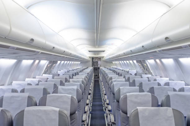 Commercial aircraft cabin with rows of seats down the aisle. Commercial aircraft cabin with rows of seats down the aisle airplane interior stock pictures, royalty-free photos & images
