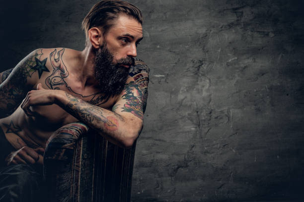 istock Tattooed bearded male sits on a chair. 938442814