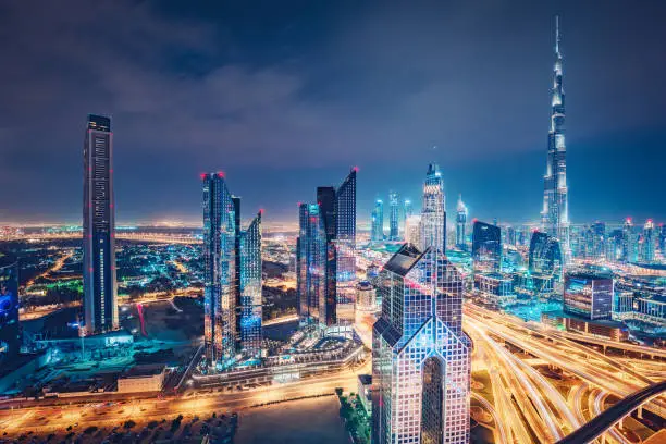 Photo of Spectacular nighttime skyline of a big futuristic city. Skyscrapers and highways of Dubai, UAE.