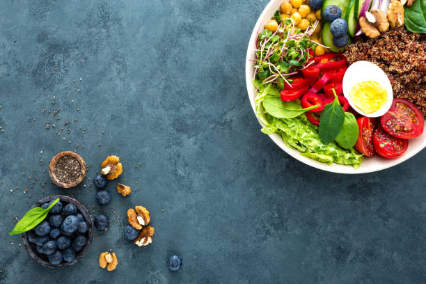 istock Buddha bowl dinner with boiled egg, chickpea, fresh tomato, sweet pepper, cucumber, savoy cabbage, red onion, green sprouts, spinach leaves, blueberry, walnuts, chia and quinoa. Healthy dish, lunch bowl. Detox diet. Balanced food. Top view 938448952