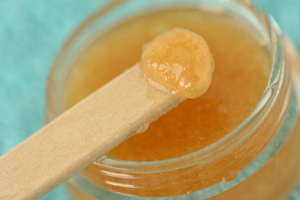 macro de maison exfoliant pour les lèvres fabriqué à partir de sucre brun, miel et huile d’olive dans un bocal en verre - exfoliation photos et images de collection