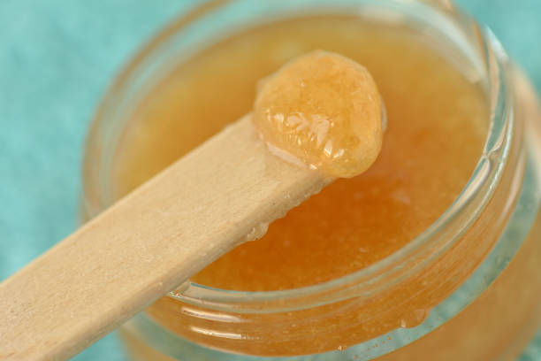 Macro of homemade lip scrub made out of brown sugar, honey and olive oil in a glass jar stock photo