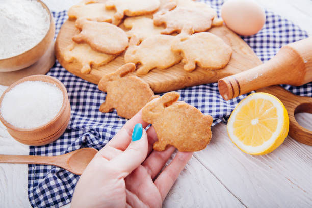 istock Woman holds Easter bunny-shaped cookie surrounded with ingredients. 938455122