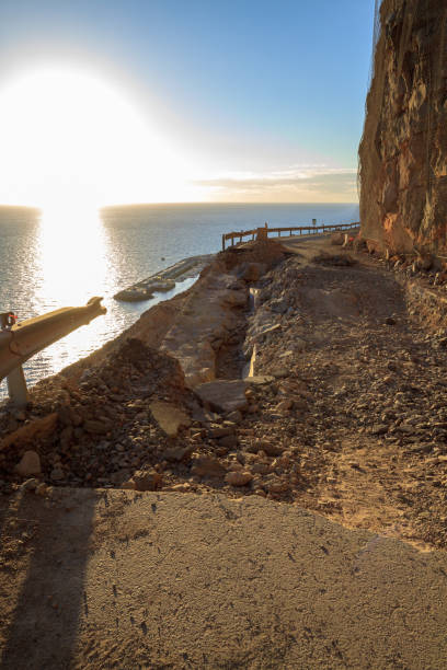 istock Falling rocks and big collapse hole on closed mountain road under the sea. 938462306