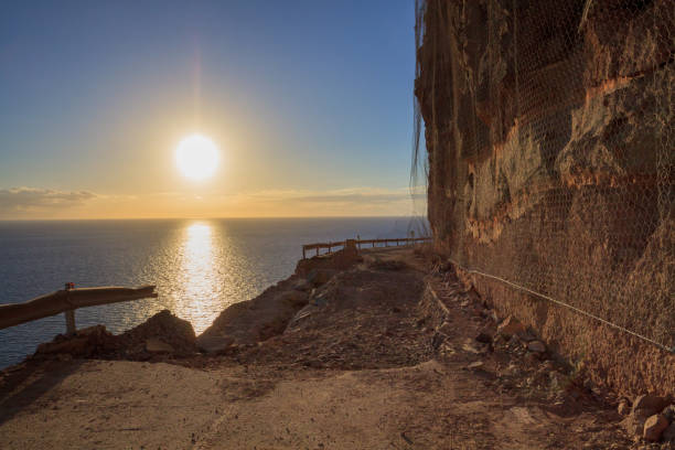 istock Falling rocks and big collapse hole on closed mountain road under the sea. 938463294