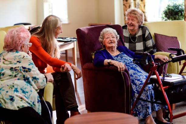 Social Gathering in a Retirement Home Women gather together in a common room in a retirement home talking and laughing common room stock pictures, royalty-free photos & images