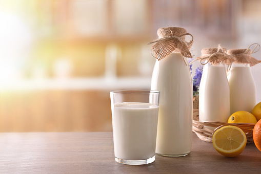 Milk containers on wooden table in sunny rustic kitchen
