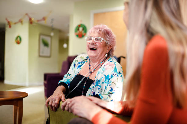 Senior Woman Laughing Senior woman talking to a younger woman who is visiting her while she is living in the care home. The senior woman has pink hair oxygen stock pictures, royalty-free photos & images