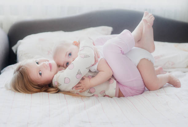 sister hugging younger sister lying on the bed