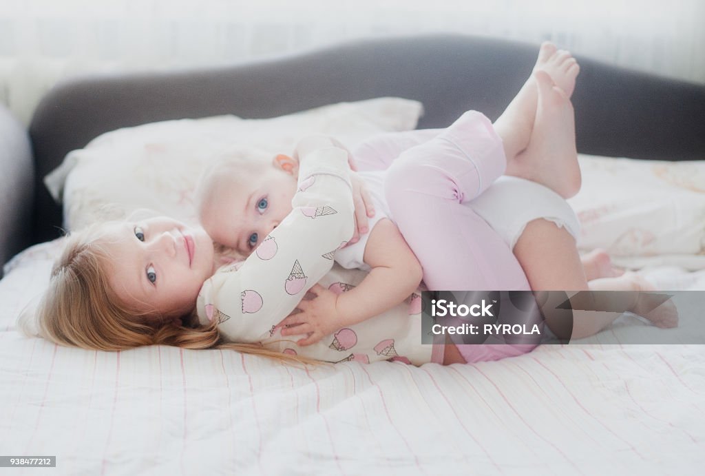 sister hugging younger sister sister hugging younger sister lying on the bed Sister Stock Photo