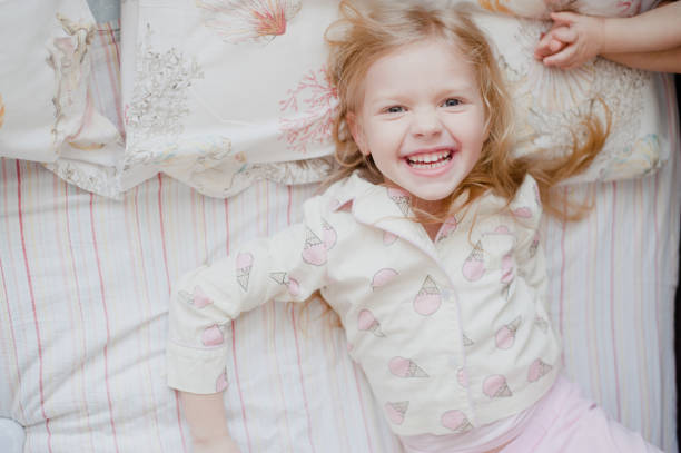 istock little girl laughing lying on bed 938477370