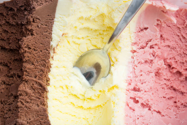 istock ice cream: A spoon in a large ice box with chocolate, vanilla and strawberry ice cream 938480860