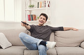 Young man watching tv using remote controller