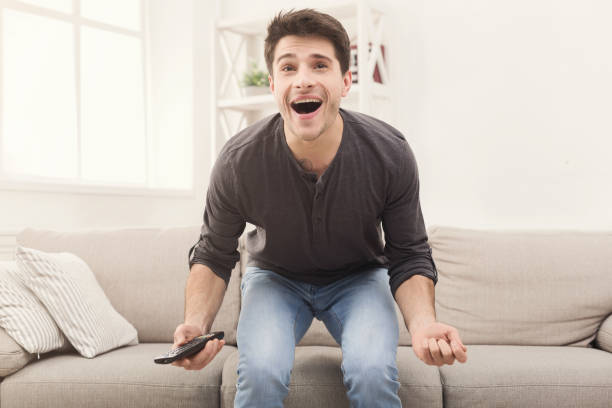istock Man watching sports on tv and supporting team 938484214