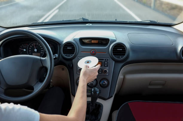 Woman inserting CD Audio while she is driving. Cause of Distracted Driving Accidents concept Woman inserting CD Audio while she is driving. Cause of Distracted Driving Accidents concept. Inside car view home cinema system stock pictures, royalty-free photos & images