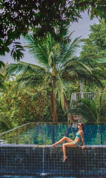 istock attractive girl sitting in bikini on poolside 938493078