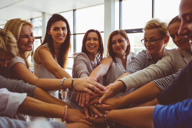 équipe féminine. groupe de joyeux femmes joignant les mains - loyalty business solidarity human hand photos et images de collection