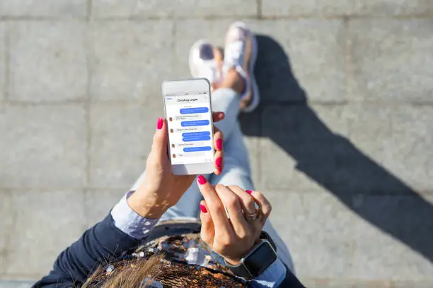 Woman using instant messaging app on mobile phone, view from above