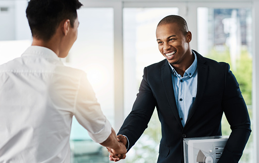 Shot of two young businessmen shaking hands in a modern office