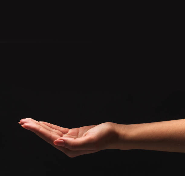 istock Woman holding palm open isolated on black 938521290