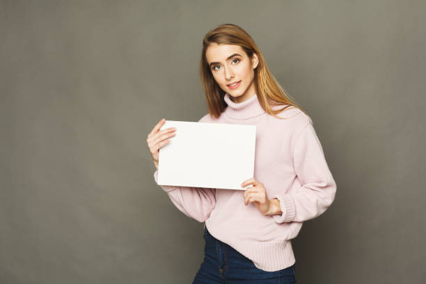 istock Young smiling woman with blank white paper 938524770