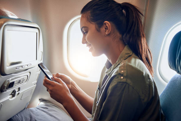 istock beautiful young woman using her smartphone in the plane 938537330